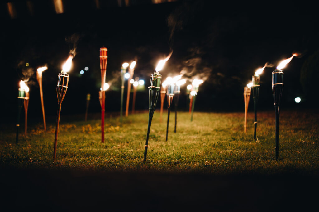 Antorchas en la hierba por la noche, arrojando llamas amarillas y reflejos.